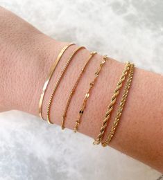 Dainty stainless steel bracelets that can be layered / stacked are ideal for mixing and matching! Combine your favorite gold link chains to create a seamless look. Plus, they are tarnish resistant and waterproof; you can wear them to the pool or gym and they won't tarnish! Herringbone (2.5 mm): 7" +1.5" extender (Clasp & Jump Ring Excluded) Box: 6.75” + 2" extender Satellite: 6" + 1.5" extender Rope (2.5 mm): 6.25" + 2" extender Dainty Gold Bracelet, Bracelet Box, Gold Link Chain, Gold Bracelets, Gold Link, Jewelry Lookbook, Minimalist Bracelet, Crown Jewels, Braided Bracelets