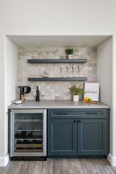 a kitchen with blue cabinets and shelves filled with wine bottles, glasses and other items