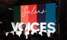 a man standing on top of a stage in front of a crowd at a business event