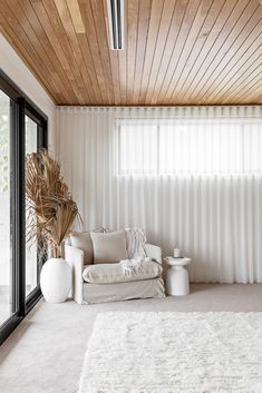 a living room with white furniture and wooden ceiling