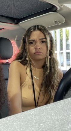 two women sitting in the back seat of a car, one is listening to headphones