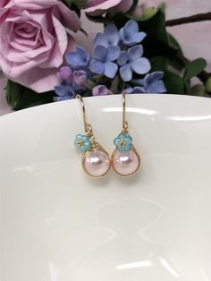 These one of a kind flowering beauties feature soft, blush pink Swarovski Crystal pearls that are meticulously wrapped in 14kt yellow gold filled wire. The braided detailing looks amazing with these pearls. Accented with gold-dusted, aqua Czech glass flowers and gracefully suspended from handcrafted French ear wires. These are perfect for Spring, Summer and for bridesmaids gifts! - All components are 14kt yellow gold filled. - Swarovski Crystal pearls, Czech Glass flower beads. - Pearl dangles a Handmade Feminine Flower Earrings For Spring, Rose Gold Flower Earrings With Pearl Drop, Rose Gold Flower-shaped Earrings With Pearl Drop, Feminine Handmade Flower Earrings, Feminine Rose Gold Earrings For Spring, Pink Earrings With Handmade Flowers For Spring, Handmade Feminine Earrings For Spring, Pink Handmade Flower Earrings For Spring, Spring Pink Earrings With Handmade Flowers