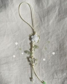 a white flower and green beaded cord on a bed sheet with beads in the shape of flowers