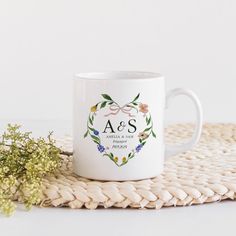 a white coffee mug sitting on top of a woven place mat next to a plant