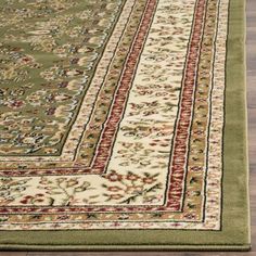 a green rug with red and white trimmings on the bottom, in front of a wooden floor