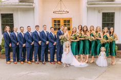 a large group of people standing in front of a white building with green dresses and ties