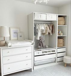 a baby's nursery closet with white drawers and clothes hanging on the rails,