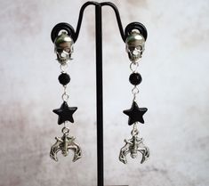 If you like your jewellery with a bit of the goth/grunge aesthetic then these bat and black star earrings with skull earposts could be just what you need! The skull stud posts are stainless steel and have stainless steel backs, below them hangs black faceted glass beads, black stars and at the bottom a silverplated bat charm. They hang approx 6cm or just under 2.5" in total and are lightweight and comfortable to wear. These skull earrings are great for goth girls, or boys, who love jewellery wit Black Metal Grunge Earrings, Black Skull Jewelry Grunge Style, Black Metal Emo Earrings, Black Skull Shaped Grunge Jewelry, Black Skull Grunge Jewelry, Black Pierced Earrings For Alternative Fashion, Nickel Free Black Alternative Earrings, Black Earrings For Alternative Fashion, Alternative Style Nickel-free Black Earrings