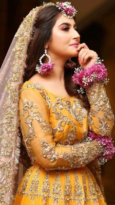 a woman in a yellow dress with pink flowers on her head and veil over her face