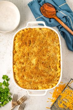 a casserole dish with cheese and parmesan on the side next to a wooden spoon