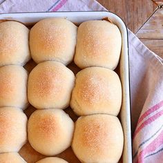 a pan filled with rolls sitting on top of a wooden table next to a red and white towel