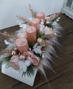 some candles are sitting on a table with flowers and feathers in it's centerpiece