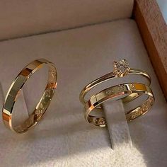 two gold wedding rings sitting in a box