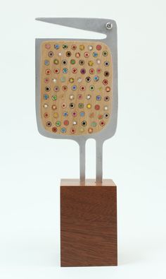 a sculpture made out of metal and wood with multicolored stones on it's face