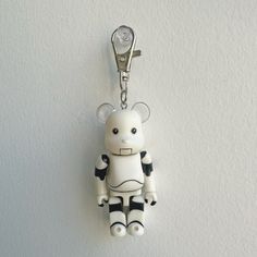 a white and black robot keychain hanging on a wall