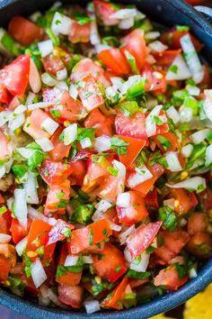 a blue bowl filled with chopped up tomatoes and green onions next to sliced lemons