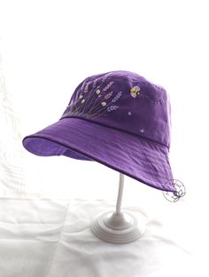 a purple hat with flowers on it sitting on top of a white table next to a wall