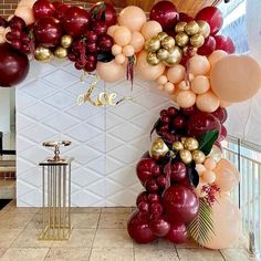 balloon arch with gold and red balloons hanging from it's sides in a room