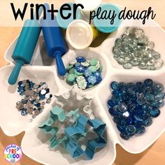 a white tray filled with blue and green items on top of a wooden table next to text that reads winter play dough