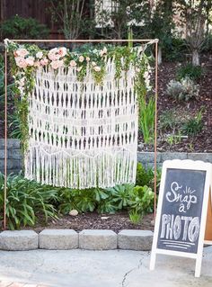 a sign that is sitting in front of some plants and flowers on the ground next to a chalkboard