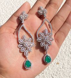 Emerald Green Earrings featuring semi precious green stone and cz diamonds. Ideal to pair with your india western sarees and formal outfits. These earrings chendelier design will elevate your look. Perfect gift for her and gift for sister. *𝐏𝐑𝐎𝐃𝐔𝐂𝐓 𝐃𝐄𝐓𝐀𝐈𝐋* * 𝐌𝐚𝐭𝐞𝐫𝐢𝐚𝐥: Brass * 𝐏𝐥𝐚𝐭𝐢𝐧𝐠: White Rhodium Plated * 𝐒𝐭𝐨𝐧𝐞: AAA-quality CZ Diamond. *𝐃𝐈𝐌𝐄𝐍𝐒𝐈𝐎𝐍𝐒* * 𝐖𝐞𝐢𝐠𝐡𝐭: 9 gm each * Length: 3.1 Inches * Width: 0.8 Inches * 𝐂𝐥𝐨𝐬𝐮𝐫𝐞: Push Back 𝐕𝐢𝐬𝐢? Western Sarees, Emerald Diamond Earrings, Emerald Green Earrings, Formal Outfits, Diamond Earring, India Jewelry, Chandelier Design, Green Diamond, Emerald Earrings