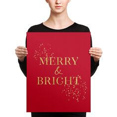 a woman holding up a merry and bright sign with gold glitters on red paper