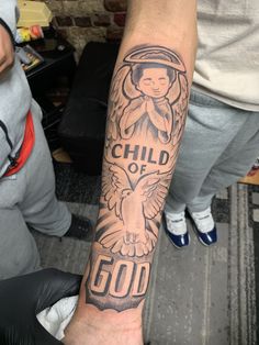 a person with a tattoo on their arm and the words child of god above it