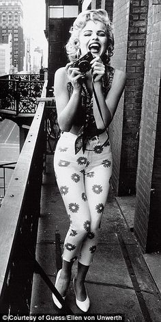 a woman standing on top of a balcony next to a building and holding a camera