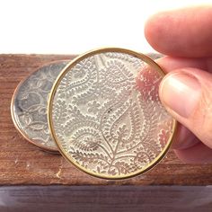 a person is holding an old coin in their hand