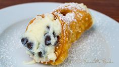 a pastry on a plate with powdered sugar and blueberries