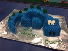 a birthday cake made to look like a blue caterpillar sitting on top of aluminum foil