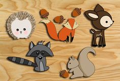 several cut outs of different animals sitting on top of a wooden surface with leaves and acorns