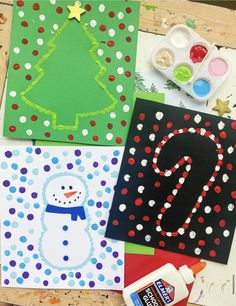 some christmas cards are sitting on a table with paint and glue in front of them