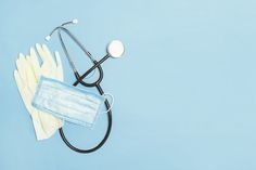 medical supplies including gloves and a stethoscope on a light blue background, top view