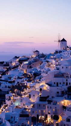 the white buildings are all lit up at night and there is a windmill in the distance