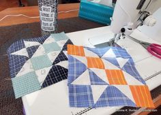 a close up of a sewing machine on a table with quilts and scissors next to it