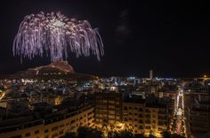 fireworks in the night sky over a city with tall buildings and lights on it's sides