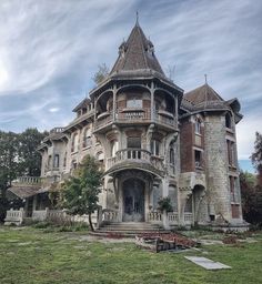 an old house with many windows and balconies on the front porch, surrounded by lush green grass