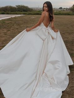 a woman in a white dress standing on the grass with her back to the camera