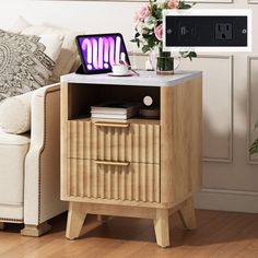 a small table with a laptop on it next to a couch and flower vases