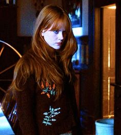 a woman with long red hair standing in a kitchen