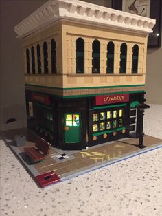 a lego model of a building on top of a tile counter with a clock above it