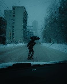 a person walking in the snow with an umbrella over their head while it's raining