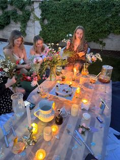 three women sitting at a table with candles on it