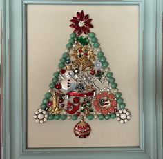 a christmas tree made out of beads and other items is displayed in a blue frame