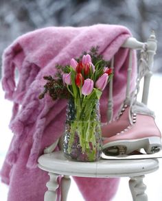 a vase filled with flowers sitting on top of a white chair next to a pink blanket