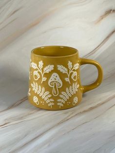 a yellow coffee mug with white designs on it