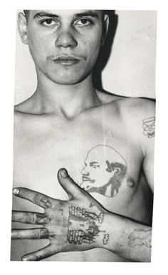 a shirtless man with tattoos on his chest and hand holding something in front of him