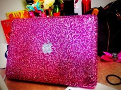 an apple laptop covered in pink sequins sitting on a desk next to other items