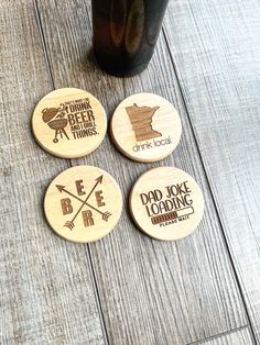 four coasters with different designs on them sitting next to a beer bottle and glass